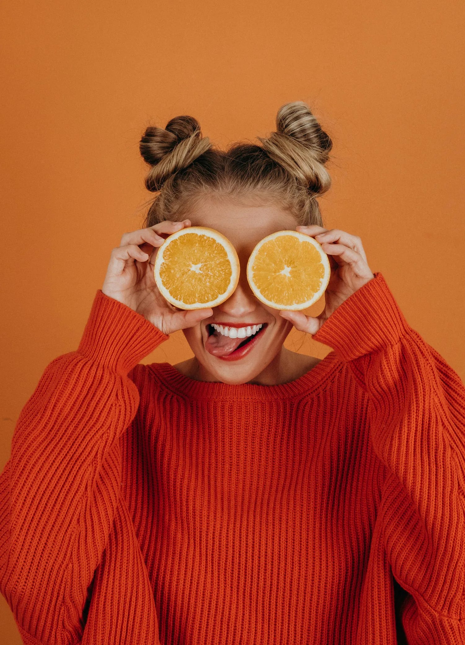 Frau hält zwei Orangenhälften vor die Augen
